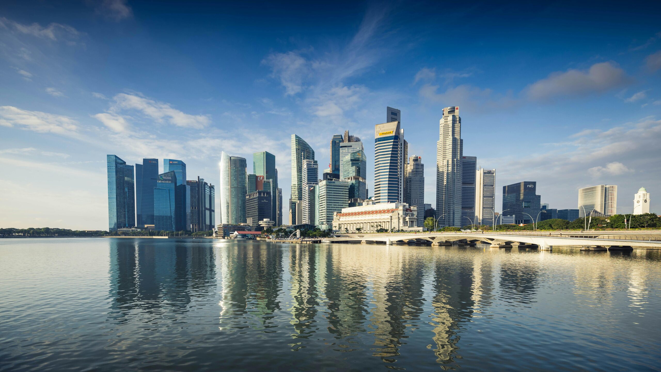 Capture of Singapore's modern skyline featuring reflective skyscrapers against a blue sky.