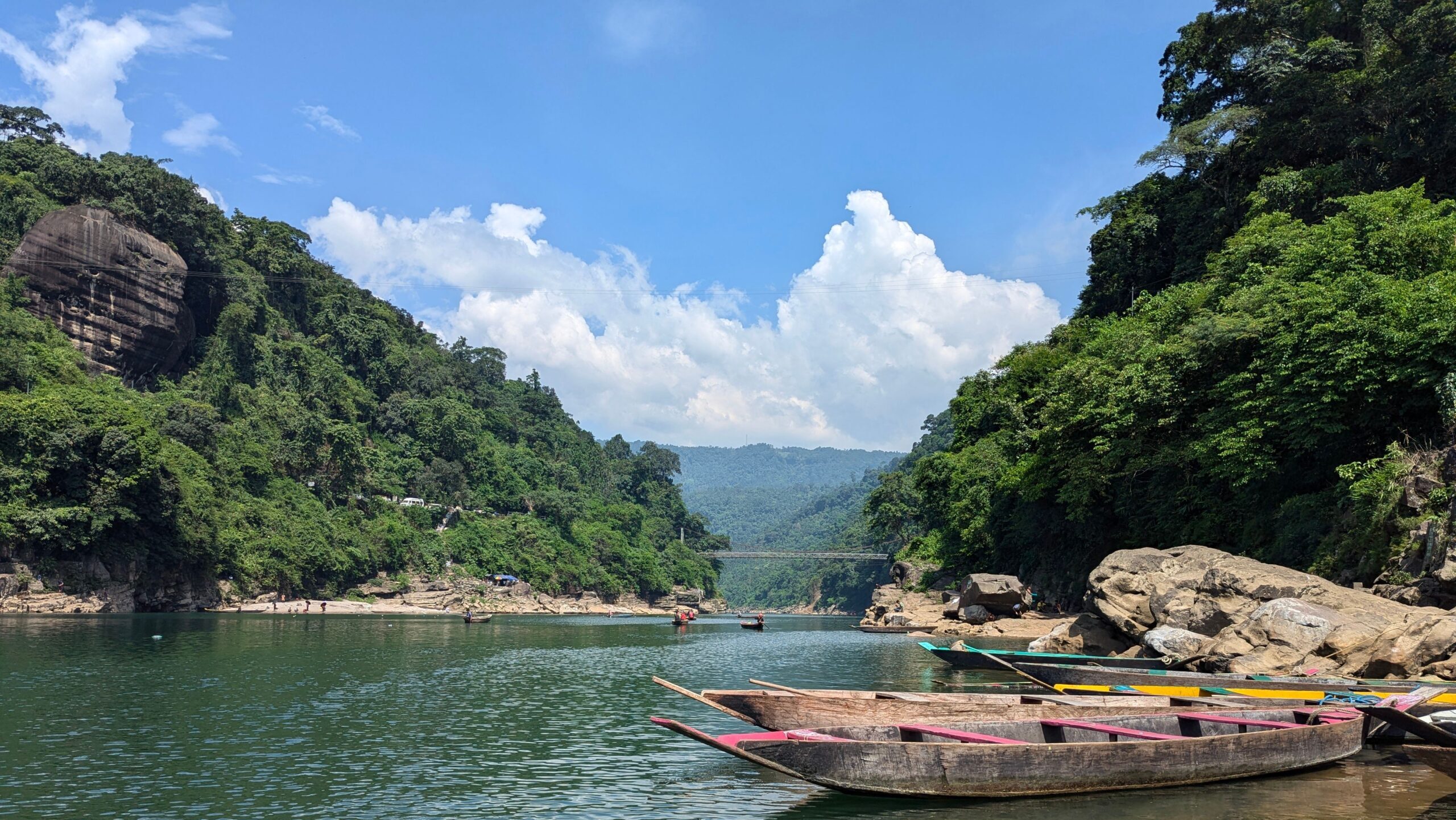 Scenic view of boats on turquoise waters with lush hills in Meghalaya, India.